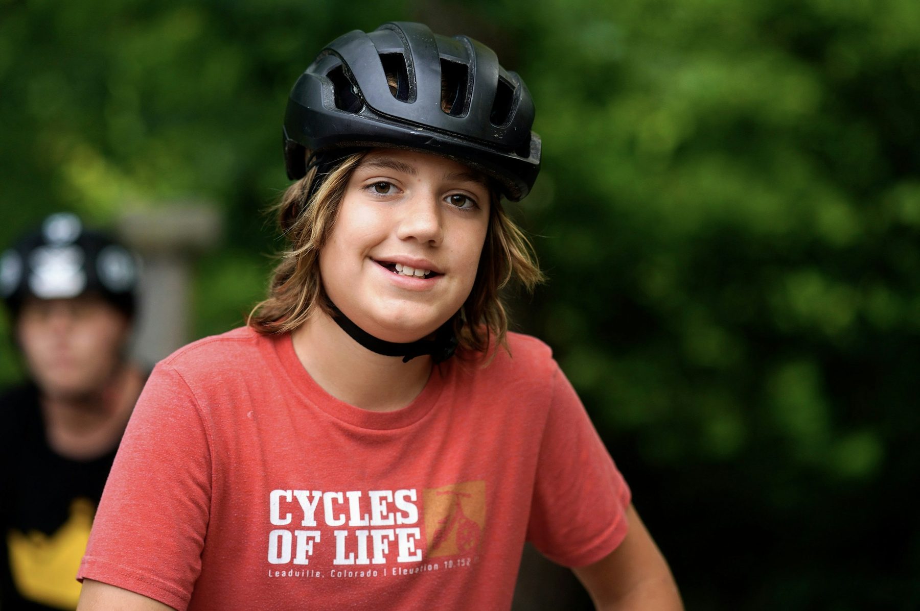 Smiling camper in helmet on a sunny trail.