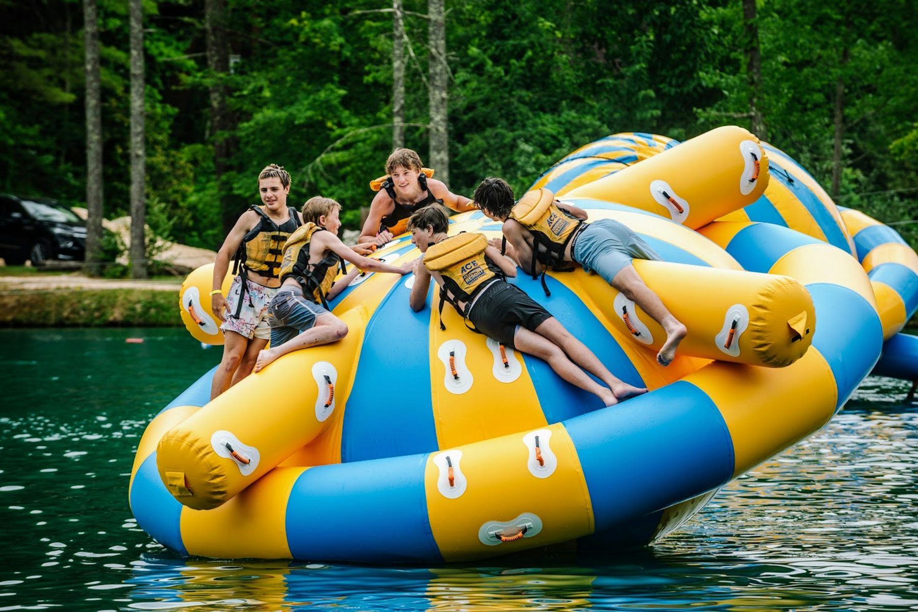Kids playing on a lake inflatable at camp.